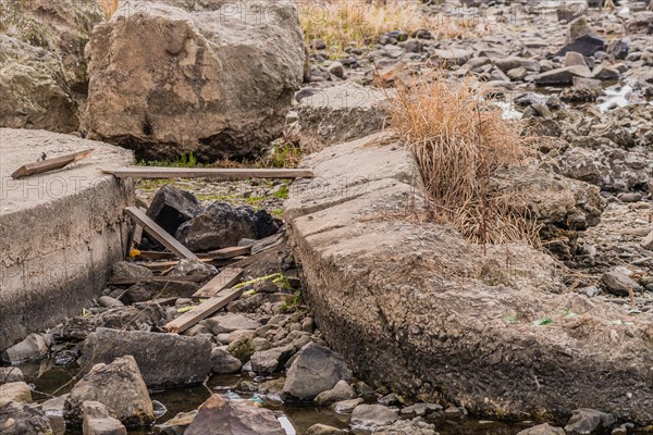 Dry stream bed showing damaged concrete structures and scattered rocks, in South Korea