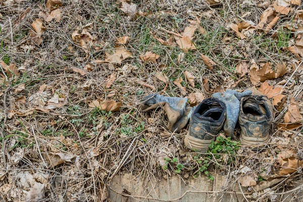 Aged shoes discarded amidst dead leaves on the ground, in South Korea