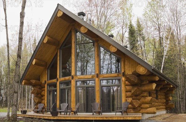 Luxurious Scandinavian style log home with large panoramic windows in spring, Quebec, Canada, North America