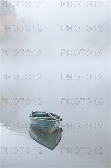 Wooden boat floating in the water, surrounded by fog, in the background barely recognisable autumn-coloured deciduous trees, canoe, boat, Diemelsee, Heringhausen, Hesse, Germany, Europe