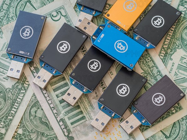 Multiple cryptocurrency USB hardware wallets spread over US dollar bills, in South Korea