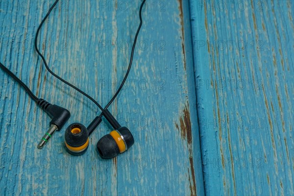 Set of black and yellow used ear buds on blue wood grain background
