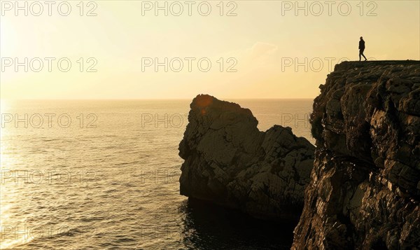 The silhouette of a solitary figure stands atop a cliff overlooking the sunset-kissed sea AI generated