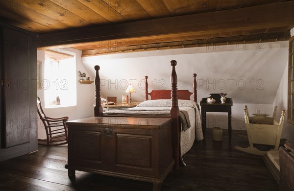 Double four-poster bed and old wooden storage chest in master bedroom on upstairs floor inside old 1785 home, Quebec, Canada, North America