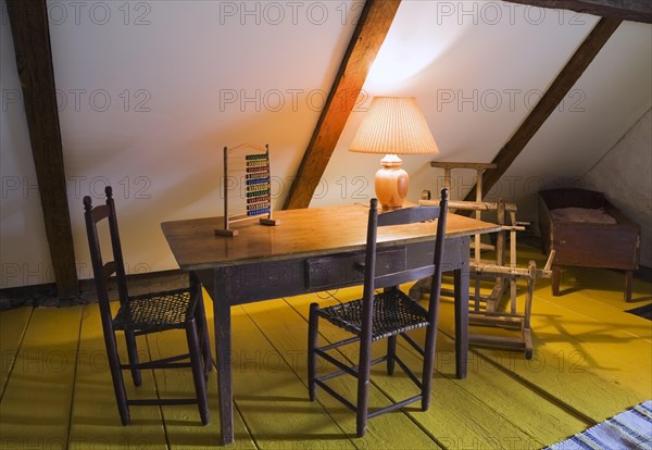 Old wooden children's play table and weaved rawhide seat chairs in bedroom on upstairs floor inside old 1785 home, Quebec, Canada. This image is property released. CUPR0260