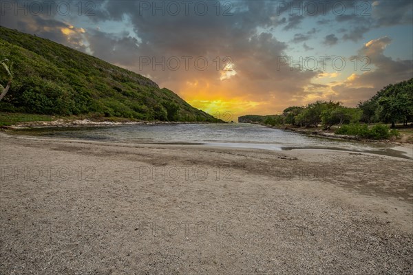 Rocky coast, long bay by the sea at sunset. Dangerous view of the Caribbean Sea. Tropical climate at sunset in La Porte d'Enfer, Grande Terre, Guadeloupe, French Antilles, North America