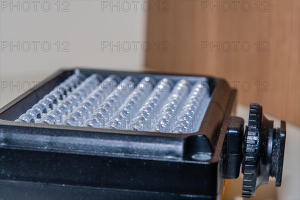 Closeup of LED continuous photographic light sitting on book shelf at home. Selective focus on front two rows of lights