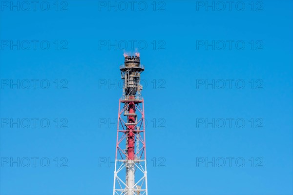 Blue sky backdrop with a fierce flame atop an industrial flare stack, in Ulsan, South Korea, Asia