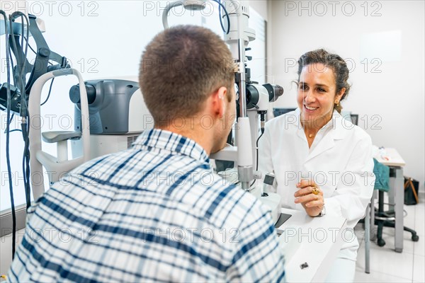 Rear view of a man talking with a female ophthalmologist during a annual check up