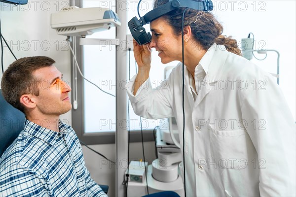 Female ophthalmologist checking the retina of a patient using the light of a retinoscope