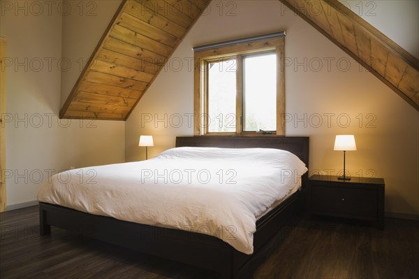 King size bed in master bedroom on upstairs floor inside contemporary style log home, Quebec, Canada. Th