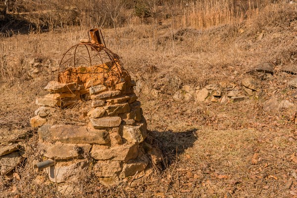 Stone structure with rusted wire frame and pipe sticking out of bottom in mountain park in Boeun, South Korea, Asia