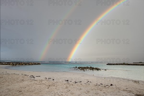 Caribbean dream beach with palm trees, white sandy beach and turquoise-coloured, crystal-clear water in the sea. Shallow bay with rainbow. Plage de Sainte Anne, Grande Terre, Guadeloupe, French Antilles, North America