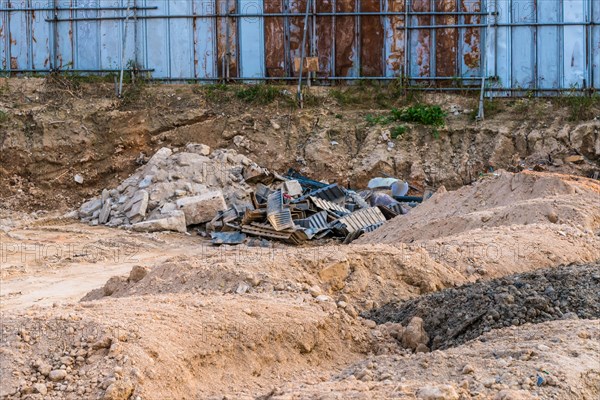 Construction site with debris, scaffolding, and piles of dirt under a blue sky, in South Korea