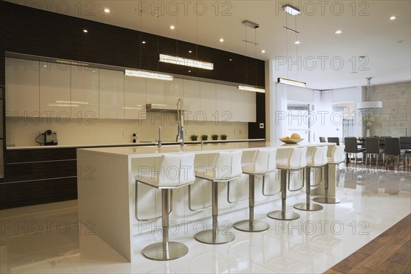 Quartz countertop island with white leather and stainless steel barsrools in spacious kitchen inside luxurious home, Quebec, Canada, North America