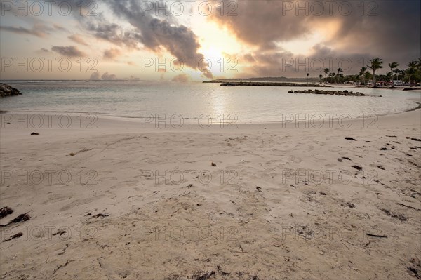 Caribbean dream beach with palm trees, white sandy beach and turquoise-coloured, crystal-clear water in the sea. Shallow bay at sunset. Plage de Sainte Anne, Grande Terre, Guadeloupe, French Antilles, North America