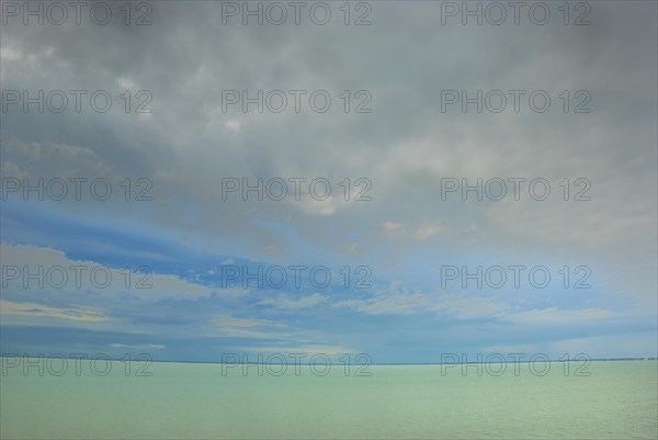 A serene seascape with a calm sea under a blue sky with wispy clouds