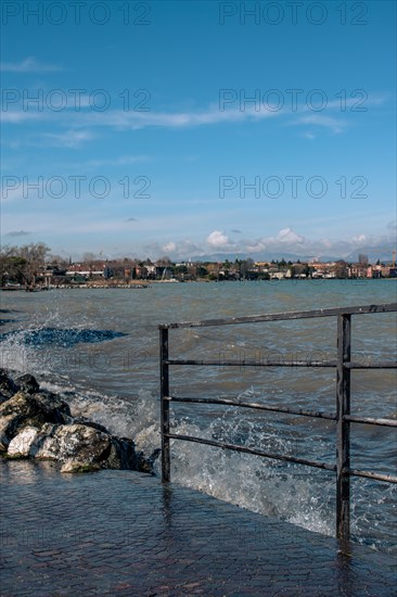 Splashing waves hitting rocks on the shore of Lake Garda, Sirmione, Lake Garda, Italy, Europe