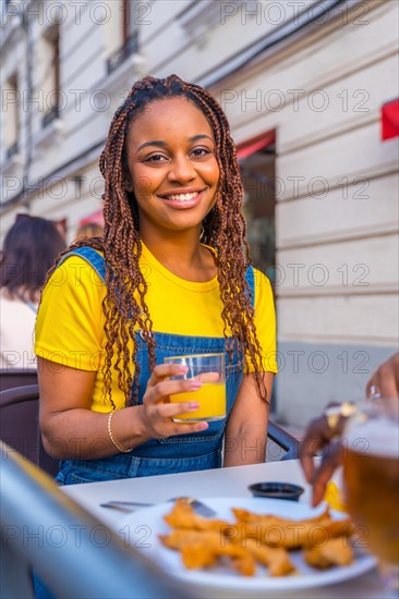 Vertical portrait of an african young woman sitting on a terrace of a restaurant