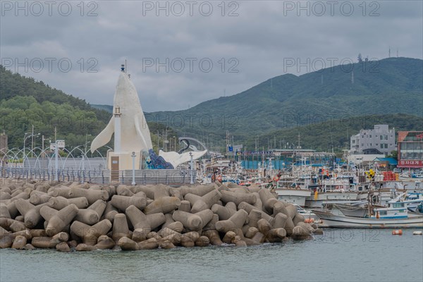 Harbor view with a white lighthouse, docked boats, and tetrapod breakwater, in Ulsan, South Korea, Asia