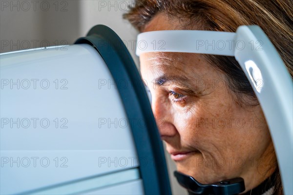 Close-up photo with side view of a mature woman receiving treatment in an innovative machine during a laser treatment for glaucoma