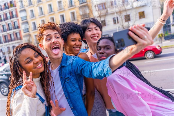 Multi-ethnic fun friends grimacing and gesturing while taking a selfie in the city