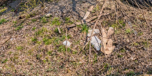 Discarded plastic and debris in a dry grassy area indicating environmental pollution, in South Korea