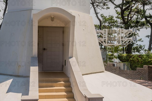 The entrance of a white lighthouse tower with a small staircase leading to the door, in Ulsan, South Korea, Asia