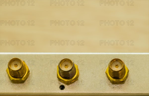 Close-up of three gold-colored coaxial cable connectors, in South Korea