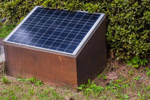 Closeup of small solar panel in front of green shrubbery in South Korea