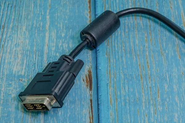 Black DVI-D monitor cable isolated on blue wood grain background
