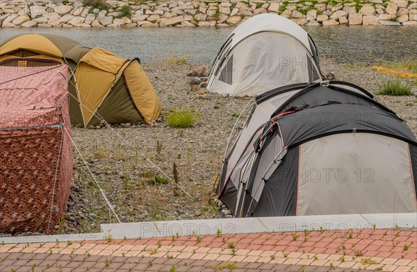 A campsite with several tents set up on a grassy and gravelly ground under an overcast sky, in Ulsan, South Korea, Asia