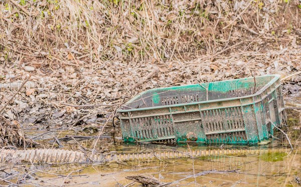 A green plastic crate abandoned in a muddy puddle, in South Korea