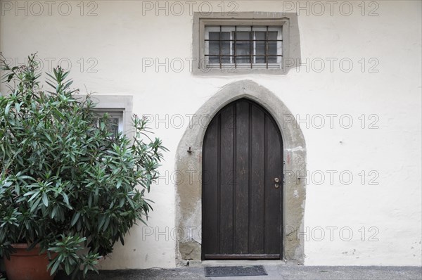 Langenburg Castle, entrance area with a wooden arched door, a small window and a potted plant, Langenburg Castle, Langenburg, Baden-Wuerttemberg, Germany, Europe