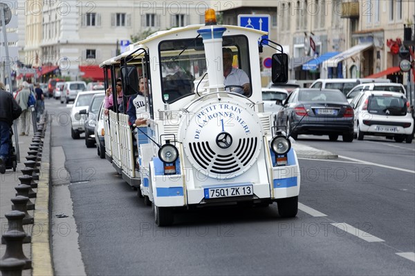 Marseille, A tourist train with passengers travelling through a busy city street, Marseille, Departement Bouches du Rhone, Region Provence Alpes Cote d'Azur, France, Europe