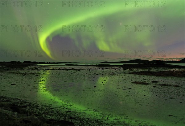 Northern Lights (Aurora Borealis) reflected in the calm waters of a shallow lake, Offersoey, Kystriksveien, FV 17, Norway, Europe