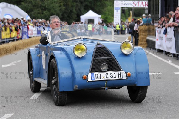 A blue vintage tricycle in a street race with a grid and spectators in the background, SOLITUDE REVIVAL 2011, Stuttgart, Baden-Wuerttemberg, Germany, Europe