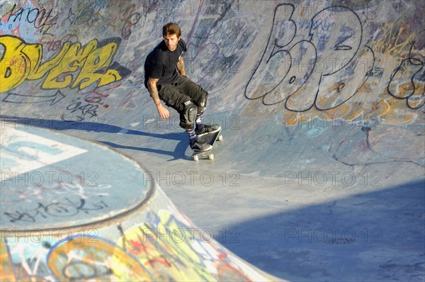 A skateboarder prepares to perform a trick in a half-pipe against the light of the evening sun, Marseille, Bouches-du-Rhone department, Provence-Alpes-Cote d'Azur region, France, Europe