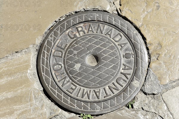 Granada, Round manhole cover with the inscription 'Granada' on a cobbled floor, Granada, Andalusia, Spain, Europe