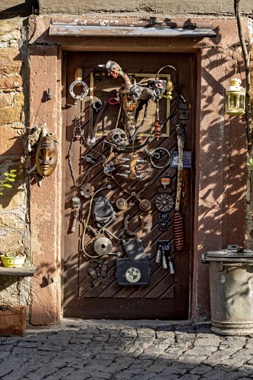 Entrance door whimsically decorated, old half-timbered house, masks, skulls, engine parts, cartridge cases, tools, old town, Ortenberg, Vogelsberg, Wetterau, Hesse, Germany, Europe
