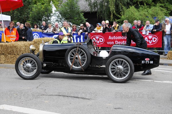 A black historic racing car is pushed by a man at a classic car event, SOLITUDE REVIVAL 2011, Stuttgart, Baden-Wuerttemberg, Germany, Europe