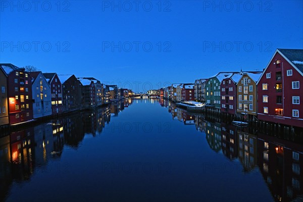 Historic warehouse buildings reflected in the river Nidelva at dusk, Bryggene, Trondheim, Norway, Europe