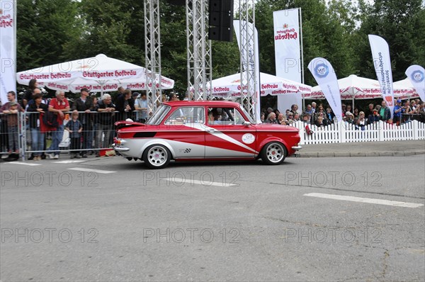 A red and white vintage car drives past enthusiastic spectators on a rally route, SOLITUDE REVIVAL 2011, Stuttgart, Baden-Wuerttemberg, Germany, Europe