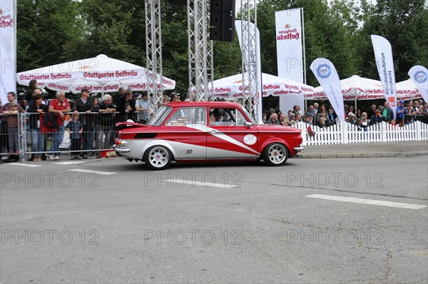 A red and white vintage car drives past enthusiastic spectators on a rally route, SOLITUDE REVIVAL 2011, Stuttgart, Baden-Wuerttemberg, Germany, Europe