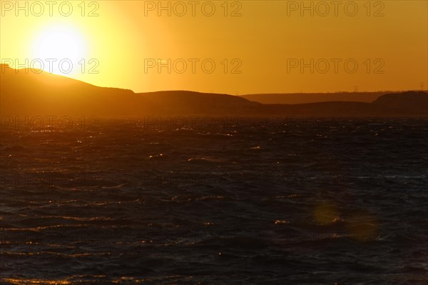 Marseille in the evening, The sun sets behind a calm sea and colours the sky orange-red, Marseille, Departement Bouches-du-Rhone, Region Provence-Alpes-Cote d'Azur, France, Europe