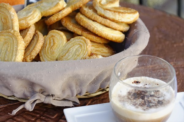 Marseille, Palmiers pastry next to a glass of coffee, arranged on a cloth, Marseille, Departement Bouches-du-Rhone, Region Provence-Alpes-Cote d'Azur, France, Europe