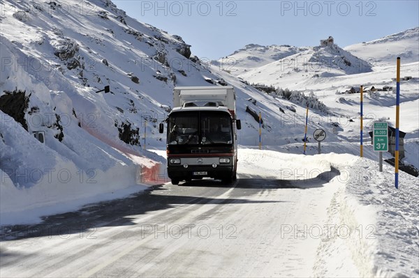 Mountains in Andalusia, Mountain range with snow, near Pico del Veleta, 3392m, Gueejar-Sierra, Sierra Nevada National Park, A red bus passes traffic signs on a snowy mountain road, Costa del Sol, Andalusia, Spain, Europe