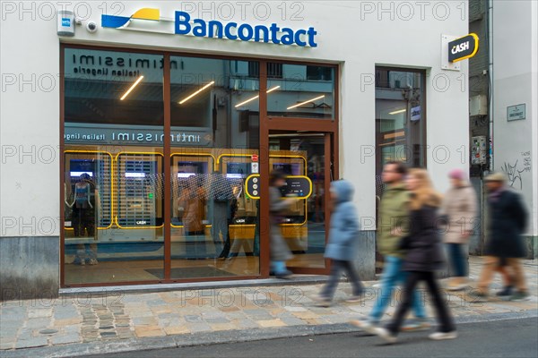 Shoppers walking past indoor ATM cash dispenser of bank neutral Bancontact CASH point in shopping street at city Ghent, Gent, East Flanders, Belgium, Europe