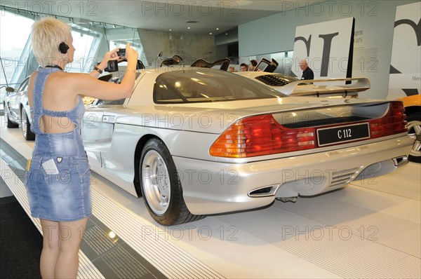 Museum, Mercedes-Benz Museum, Stuttgart, Woman takes a photo of the rear of a silver Mercedes-Benz C112 in a showroom, Mercedes-Benz Museum, Stuttgart, Baden-Wuerttemberg, Germany, Europe