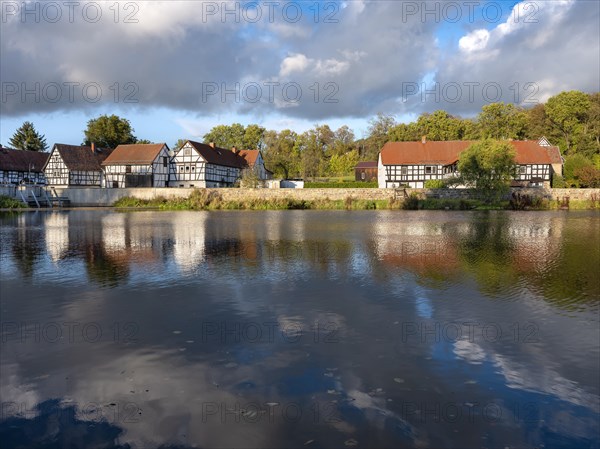 Half-timbered houses are reflected in the river Weisse Elster, Wuenschendorf (Elster), Thuringia, Germany, Europe